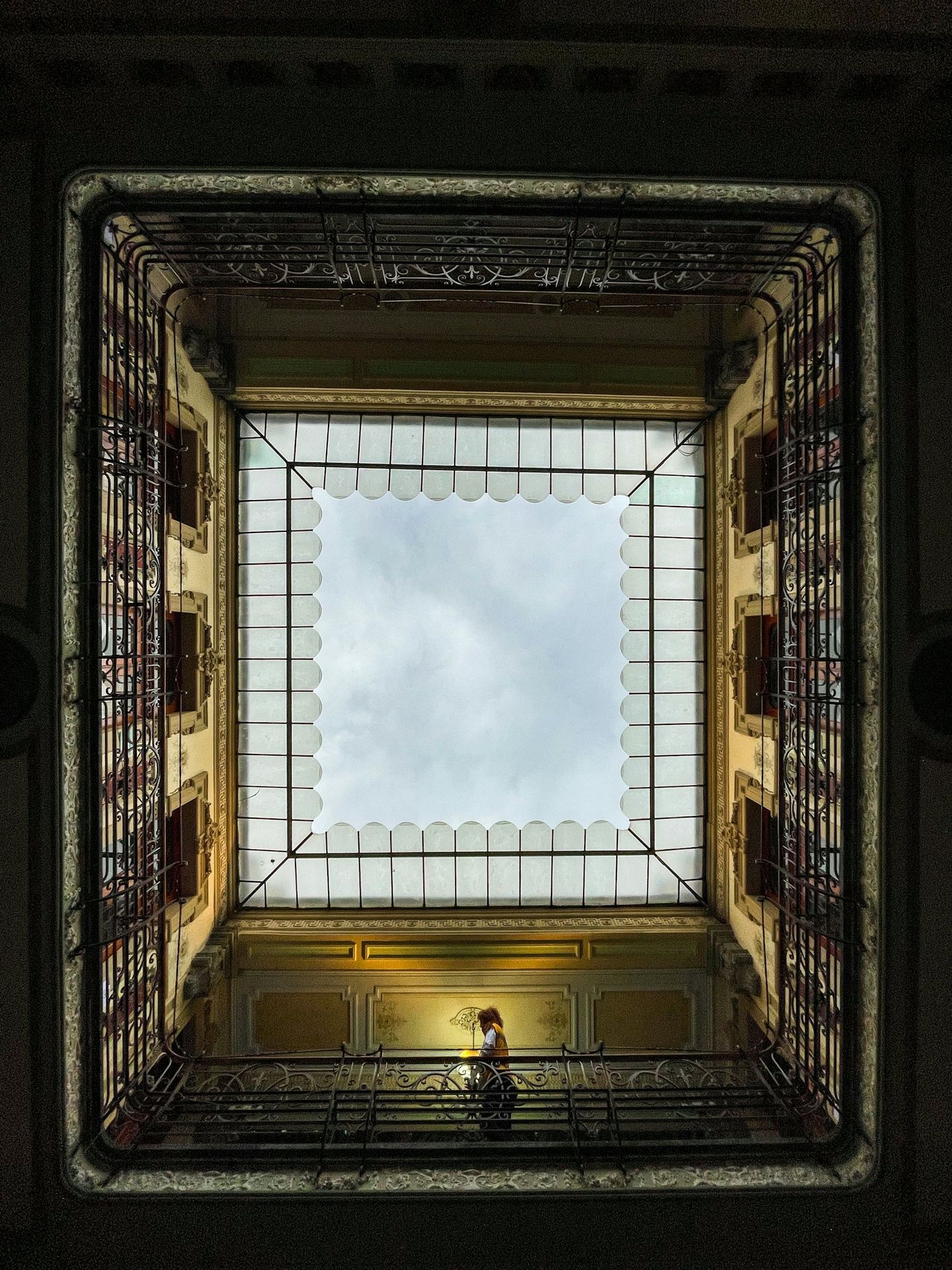 a person sitting on a bench in a room with a skylight